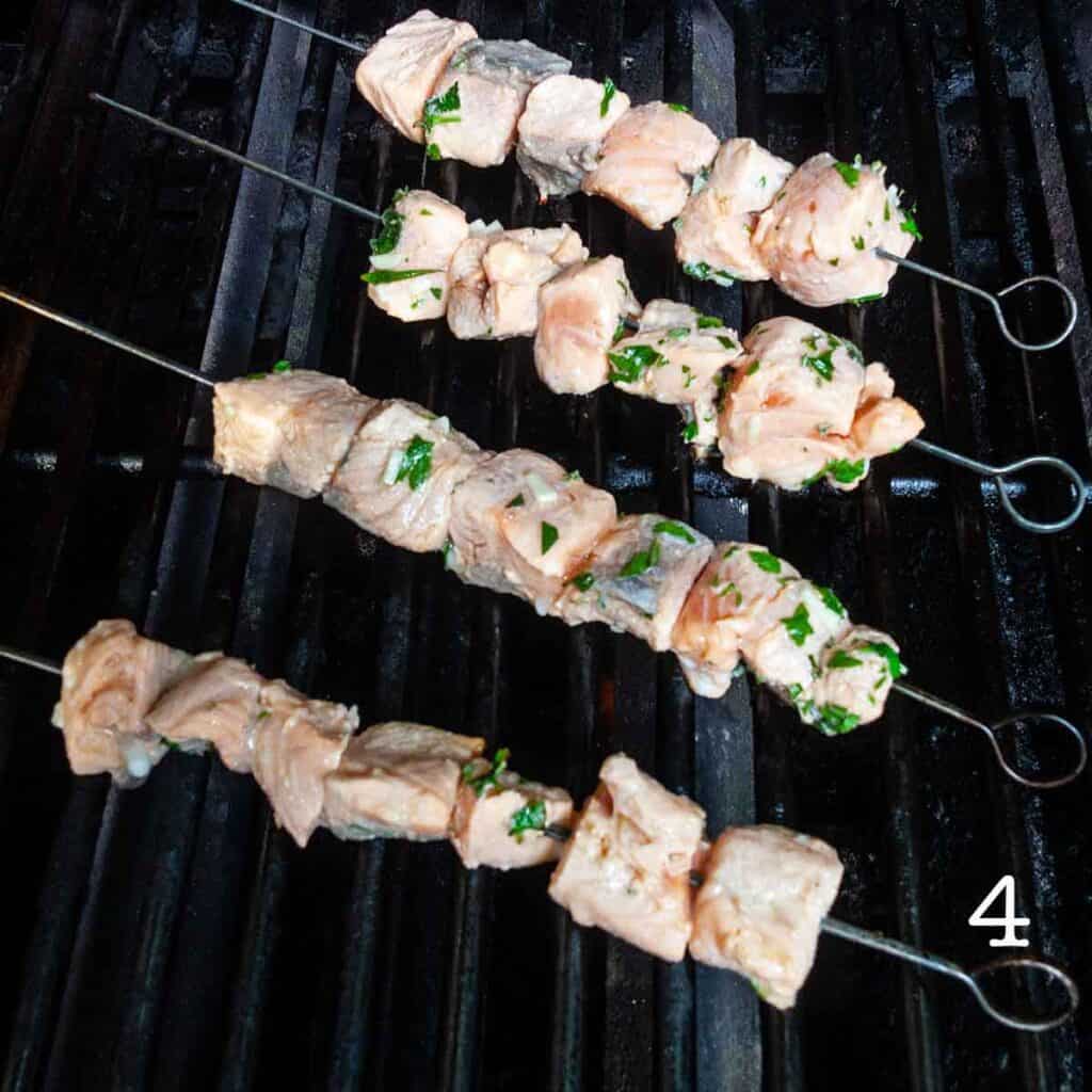 Four salmon kebabs on a grill.