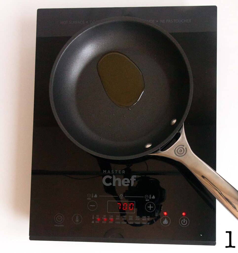 Oil being heated in a small skillet on a portable induction stove.