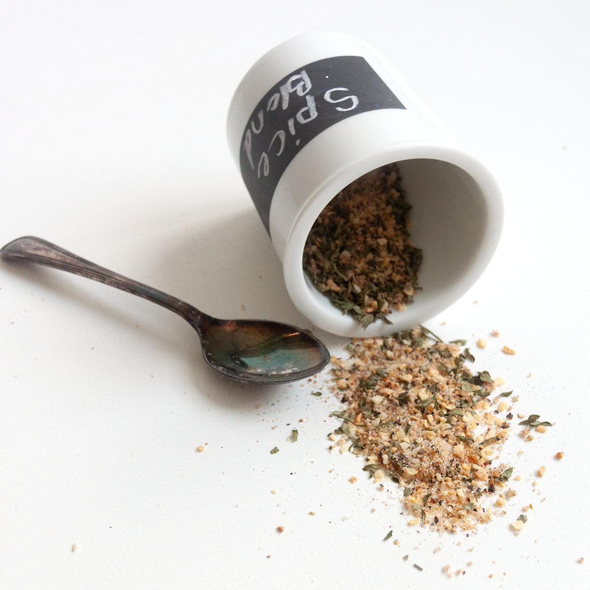 A jar of spice blend tipped on its side with some spice mix spilling out.