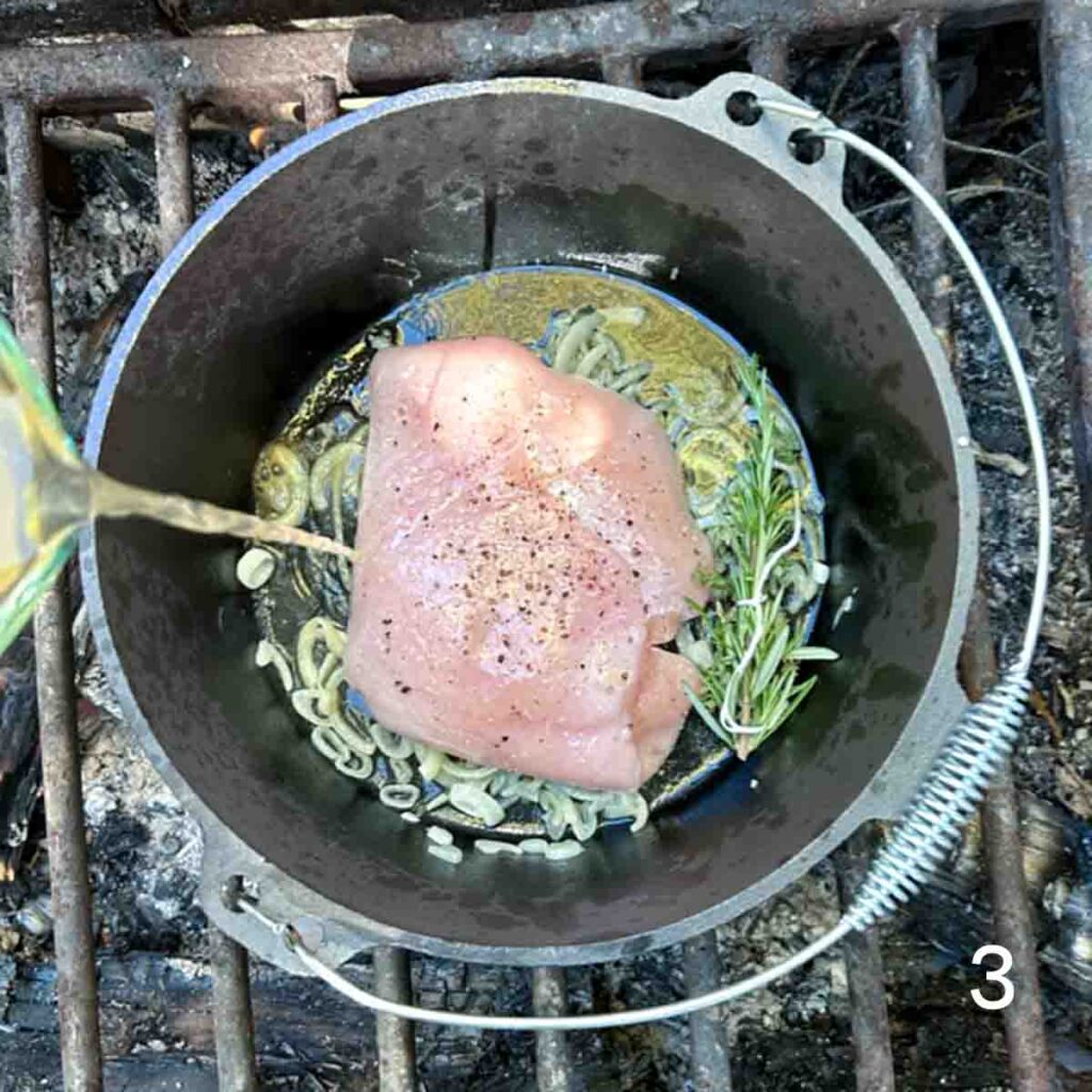 A whole turkey breast in a Dutch oven over a fire.