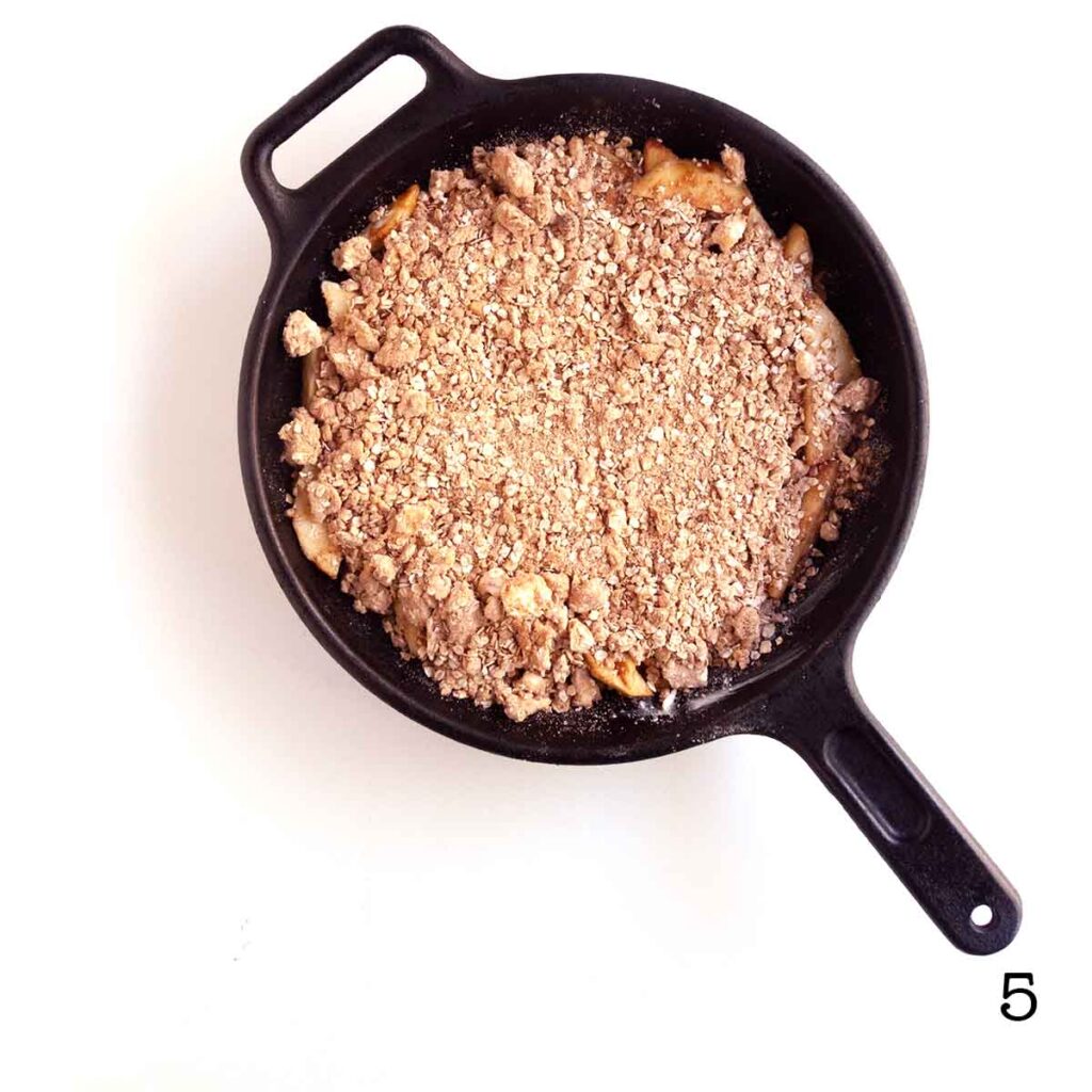 An uncooked apple crisp in a cast iron skillet.