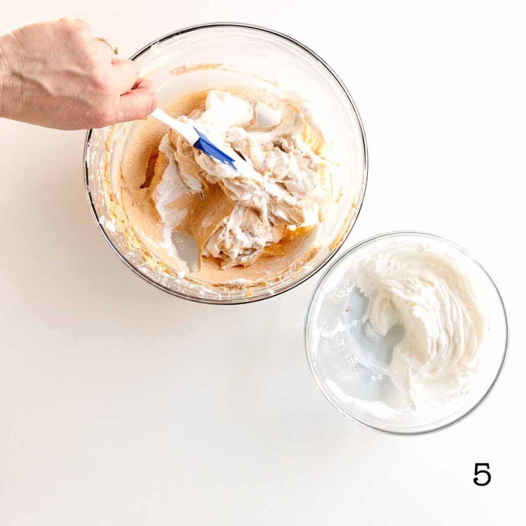 A person folding whipped cream into a bowl of pumpkin cheesecake filling.