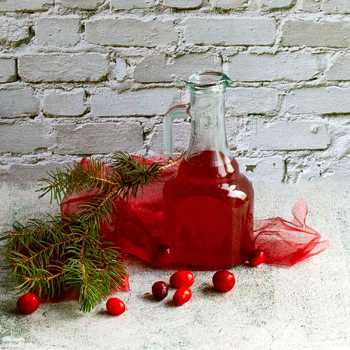 A glass bottle filled with cranberry simple syrup.