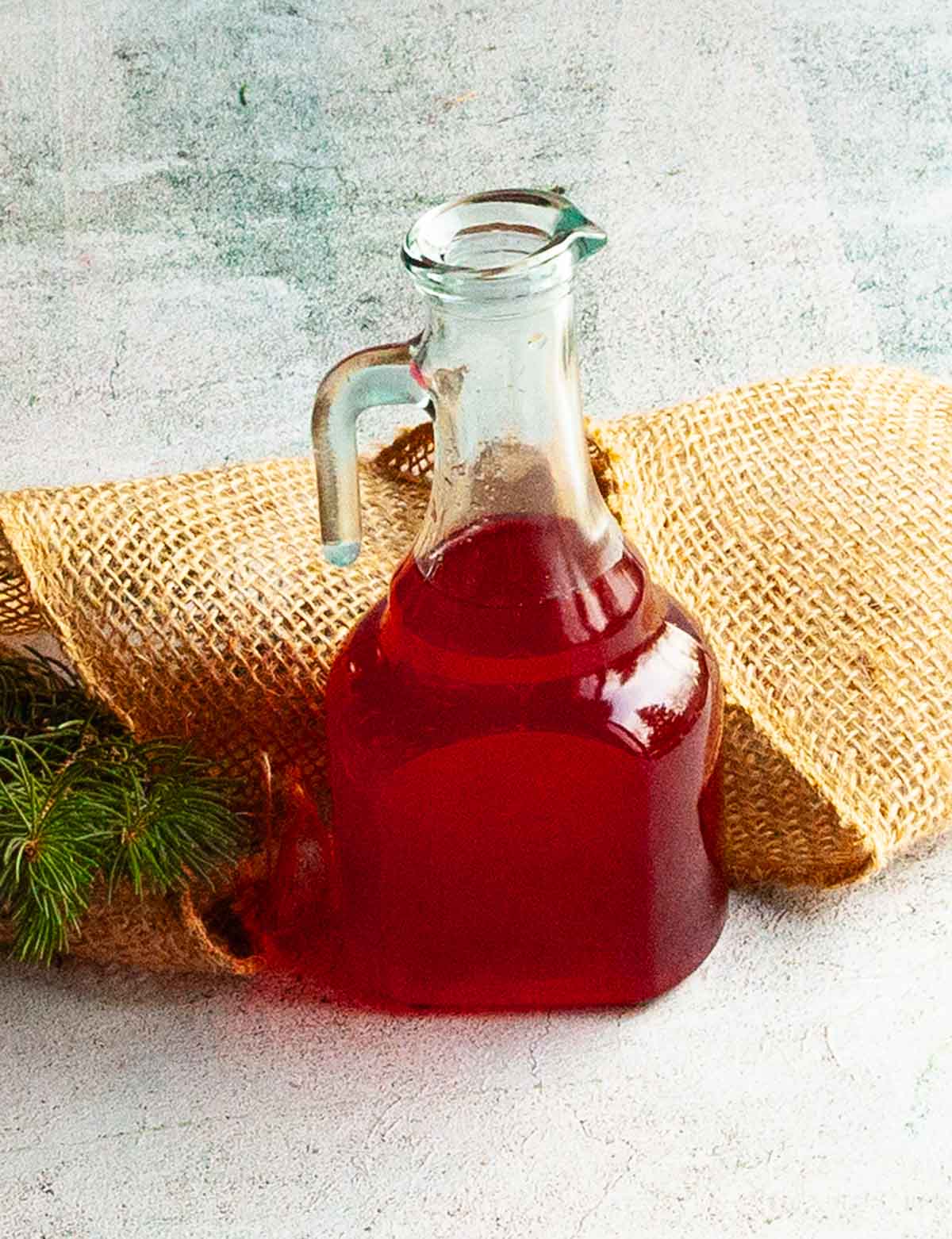 A glass bottle filled with cranberry simple syrup.