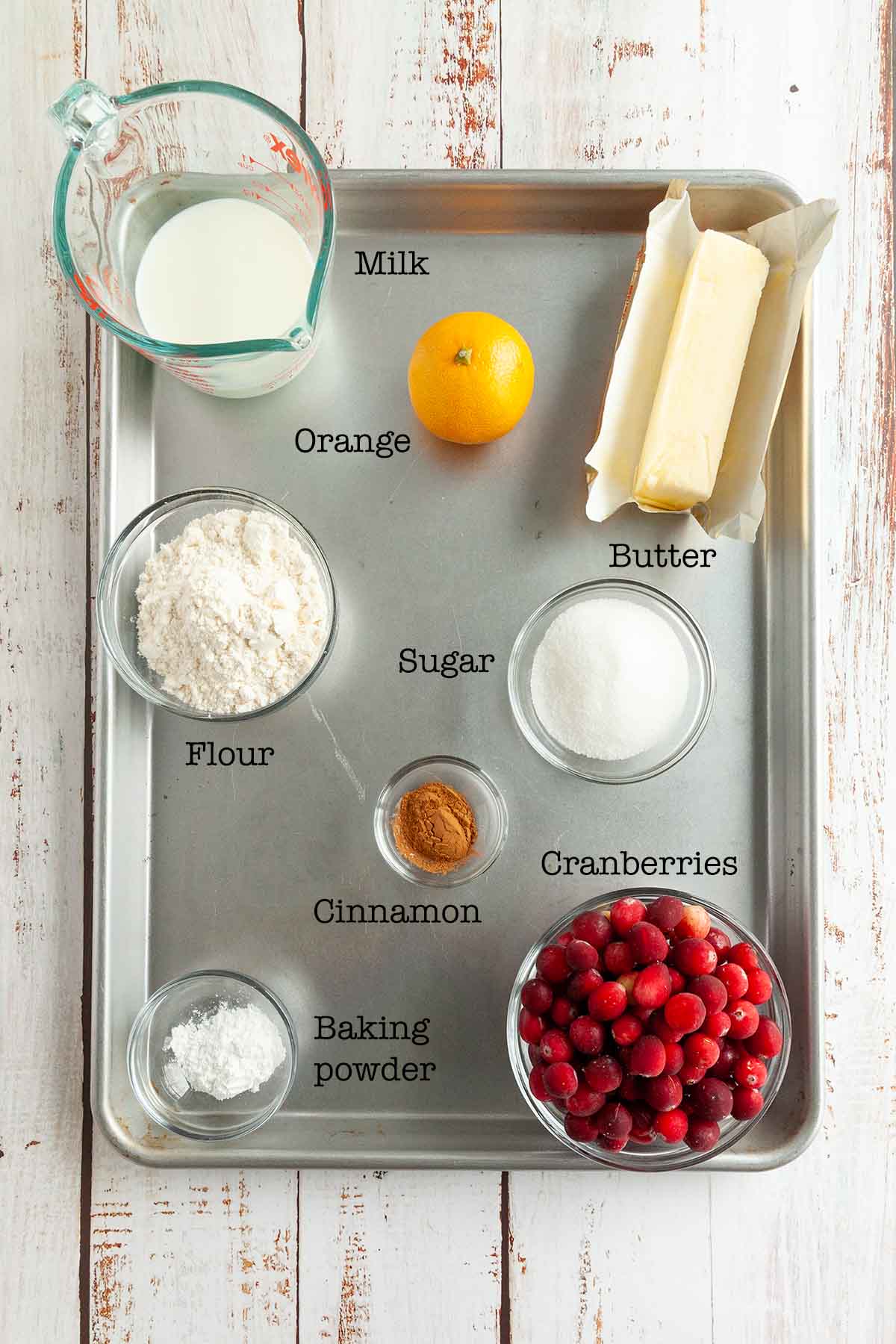 Ingredients for cranberry cobbler--flour, sugar, butter, orange, cranberries, baking powder, and milk.