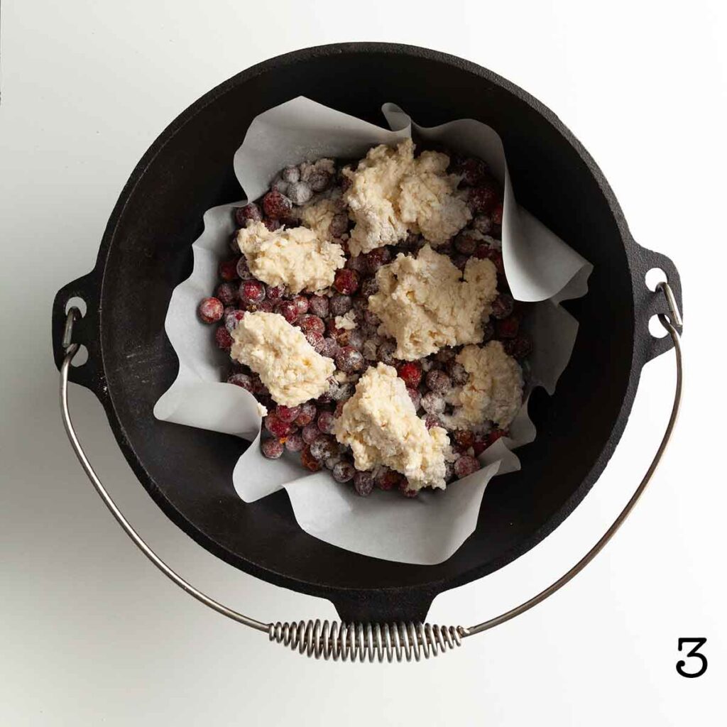 Uncooked cranberry cobbler in a Dutch oven.