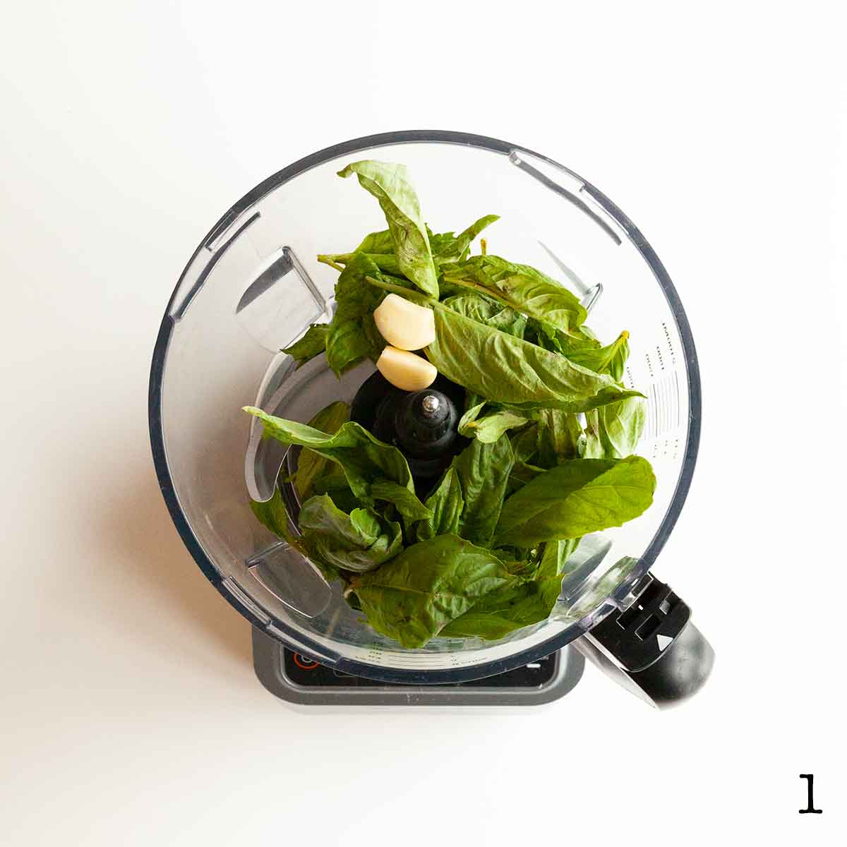 Fresh basil leaves and garlic in a food processor.