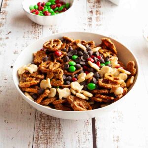 A bowl of pretzel rail mix with small bowls of M&Ms and fish crackers nearby.