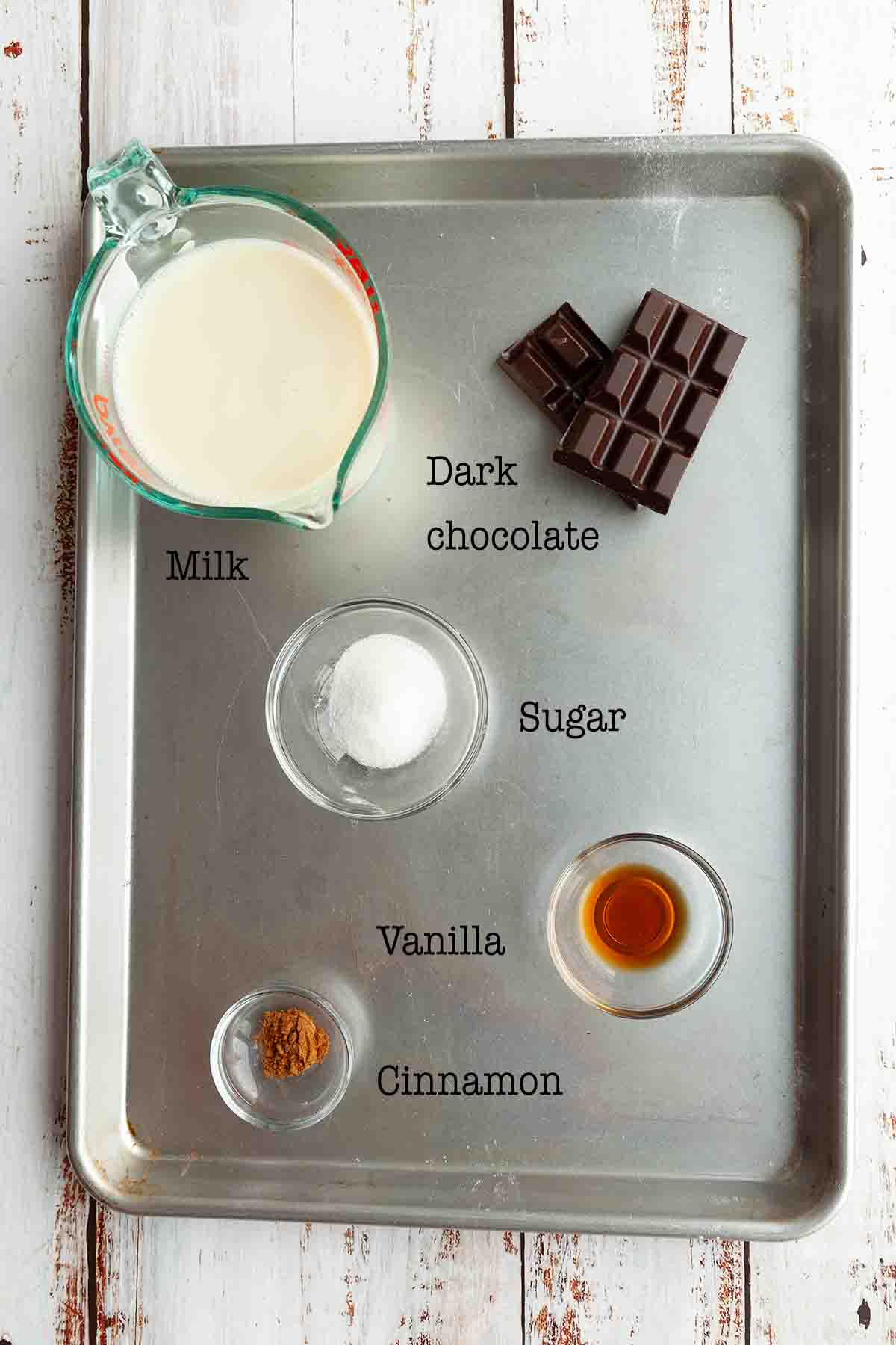 Ingredients for dark hot chocolate--dark chocolate, milk, sugar, vanilla, and cinnamon.