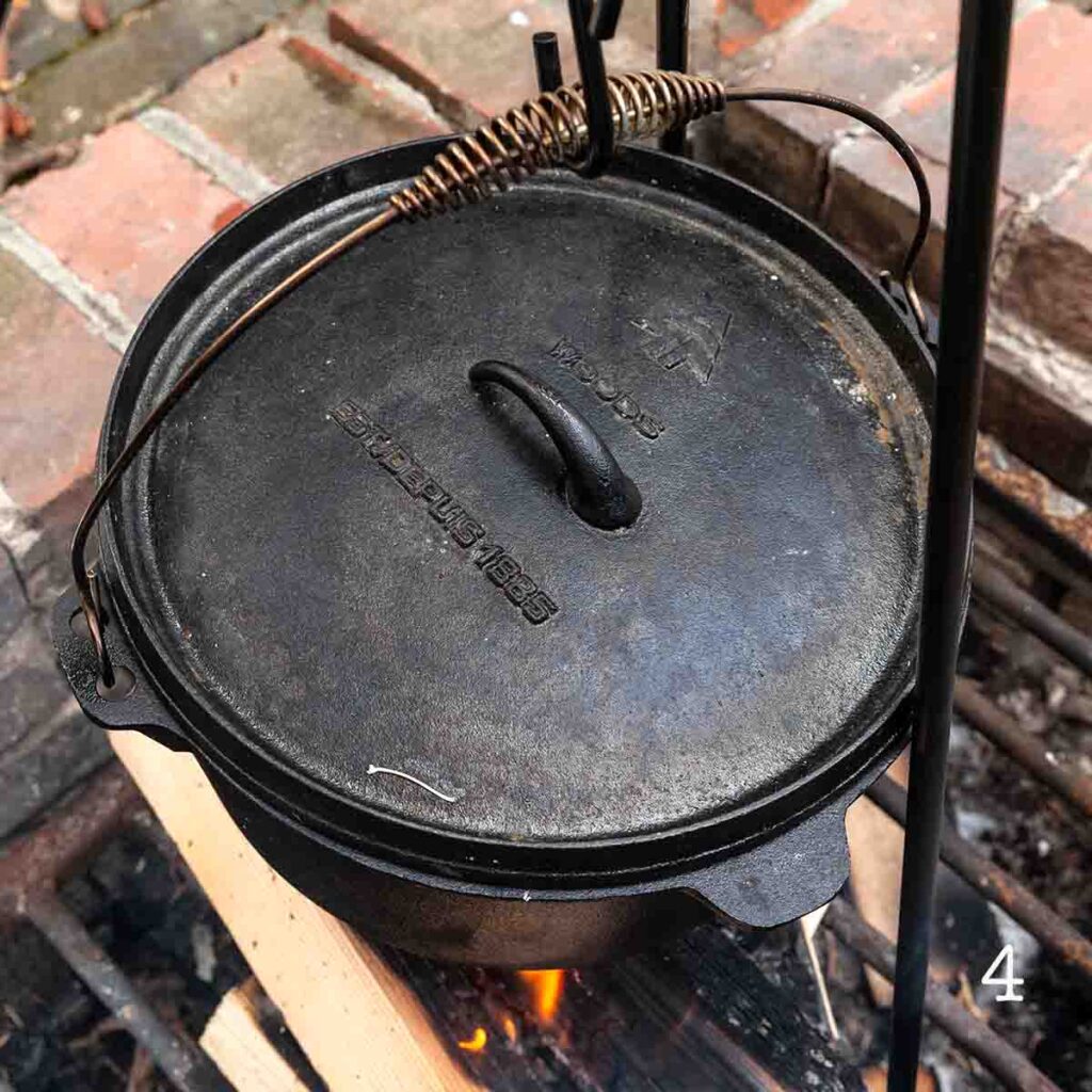 A covered Dutch oven set over a fire.