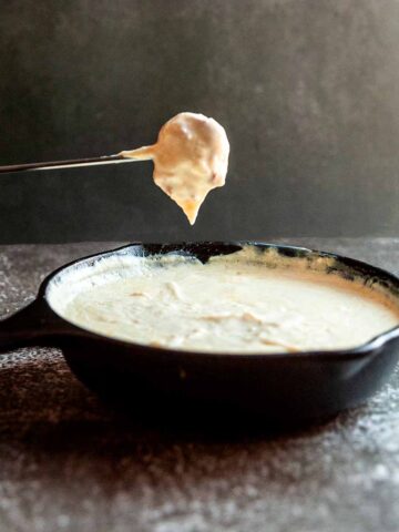 A cube of bread on a fondue fork, covered in Swiss cheese dip.