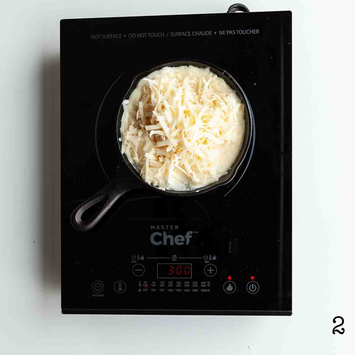 Swiss cheese dip melting in a skillet on an induction burner.