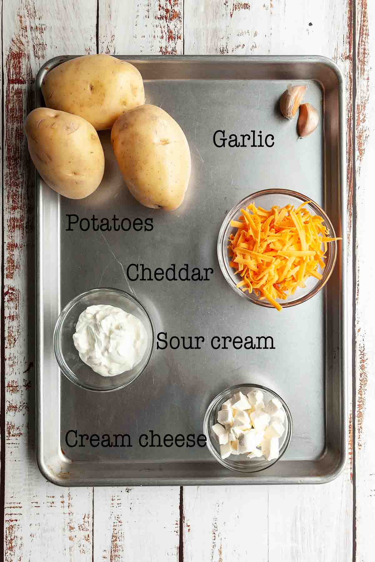 Ingredients for cheesy garlic mashed potatoes--potatoes, garlic, cheddar, sour cream, and cream cheese
