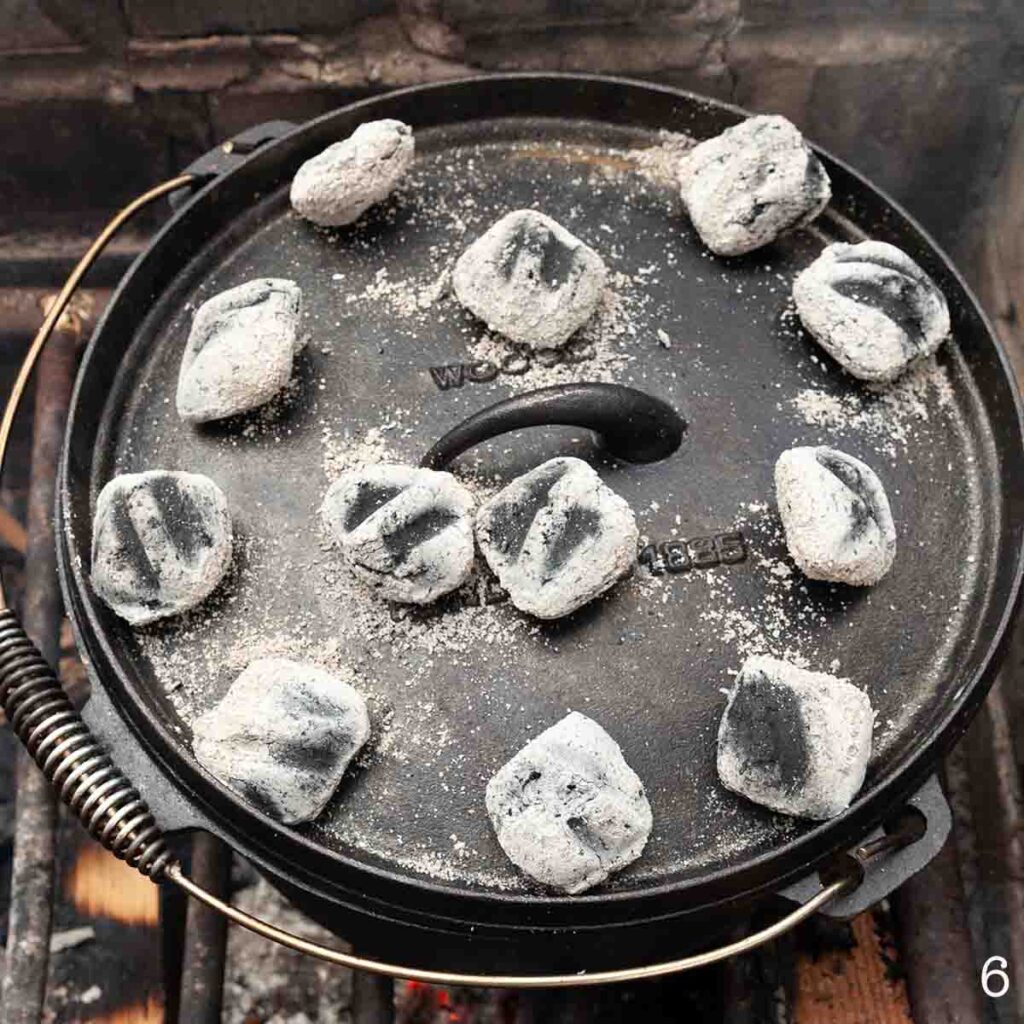 Hot coals on the lid of a Dutch oven over a fire.