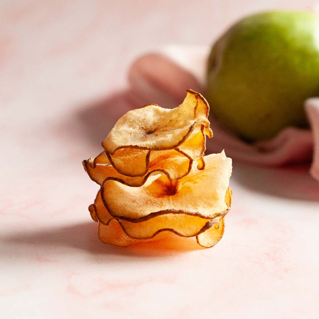 A stack of pear chips with a pear in the background.