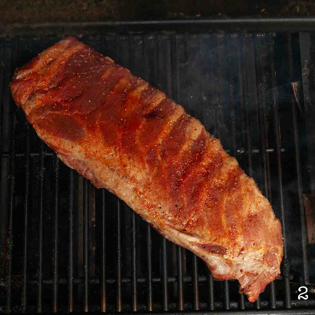 A rack of ribs cooking on a grill.