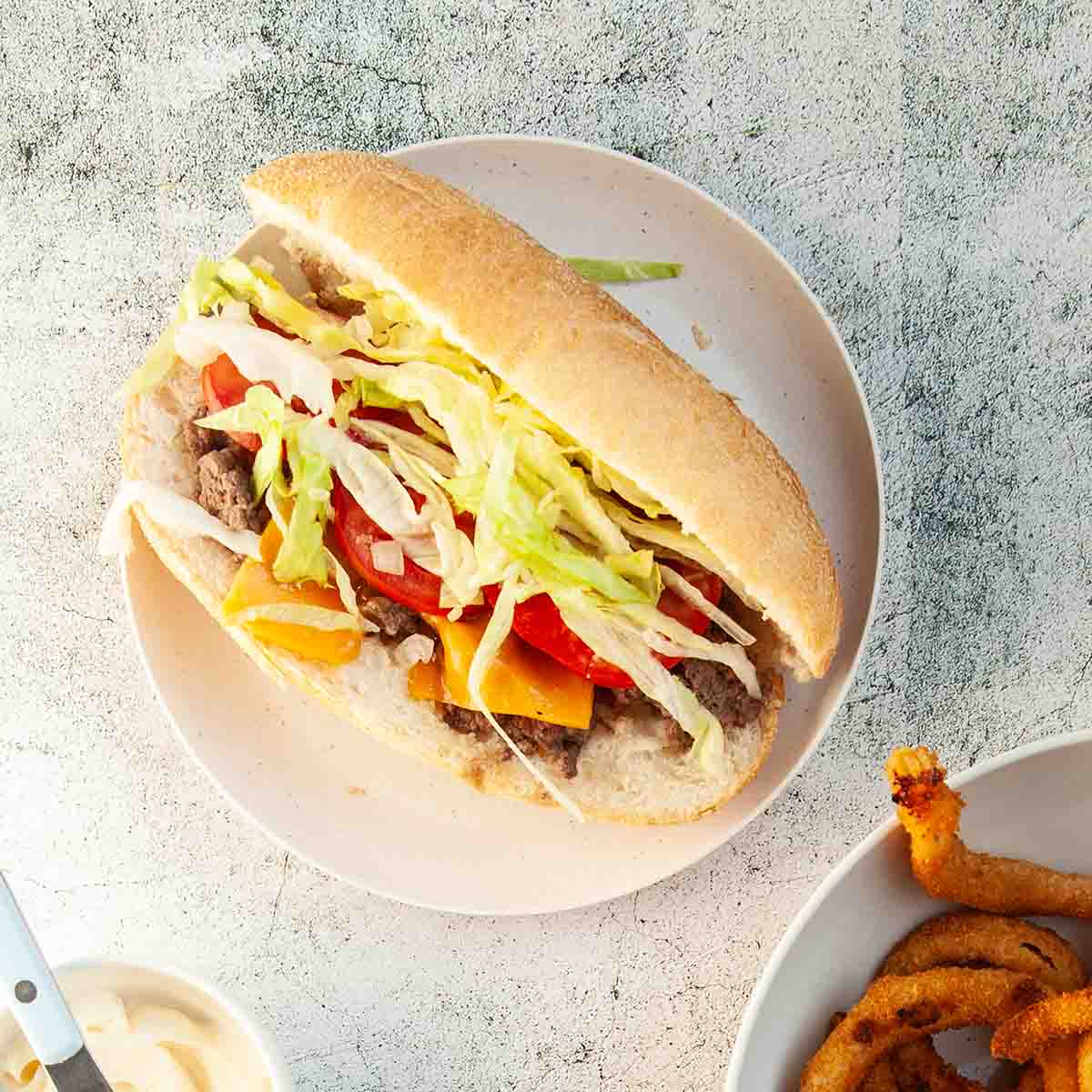 A Blackstone chopped cheese sandwich with lettuce and tomato.