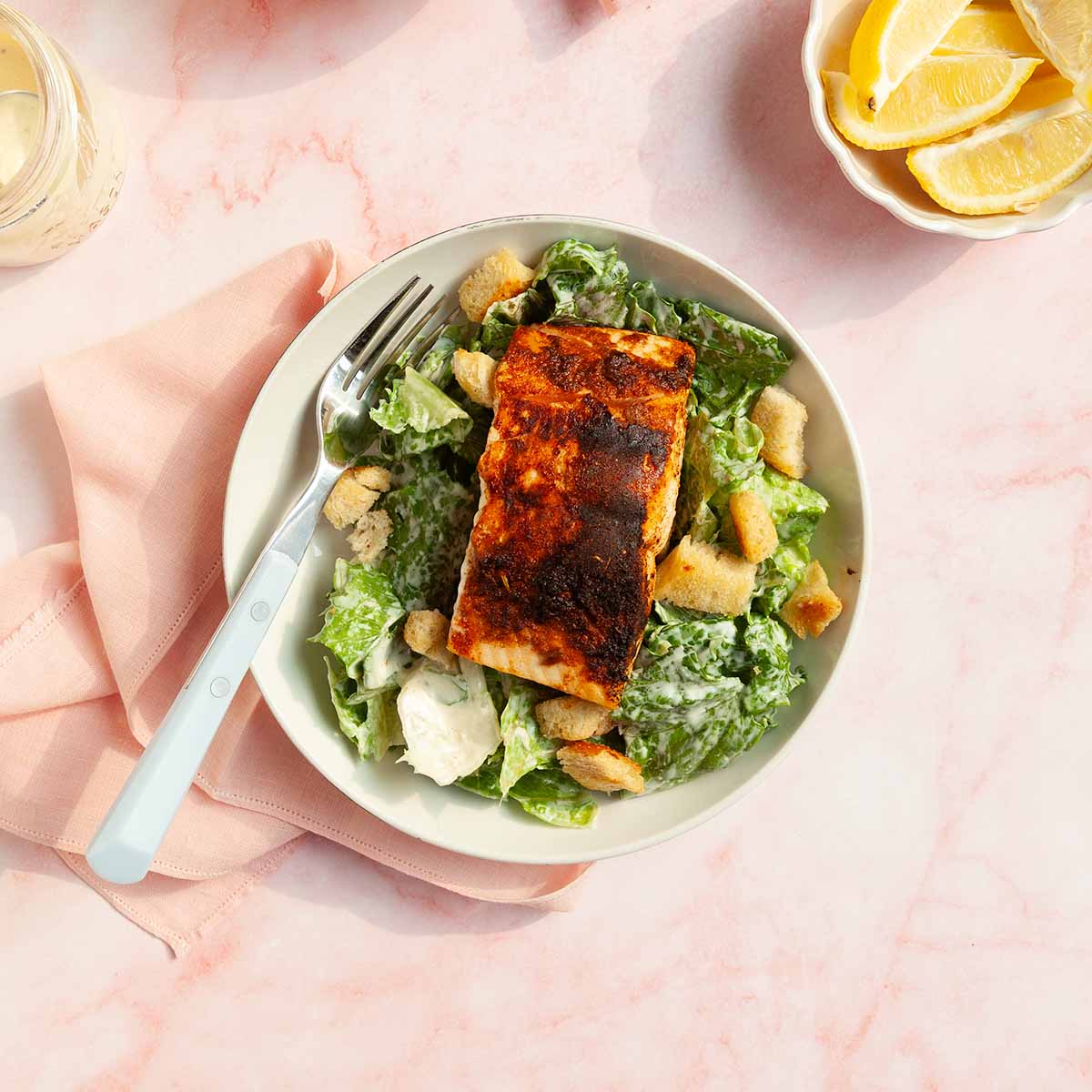 A piece of blackened salmon on a Caesar salad.