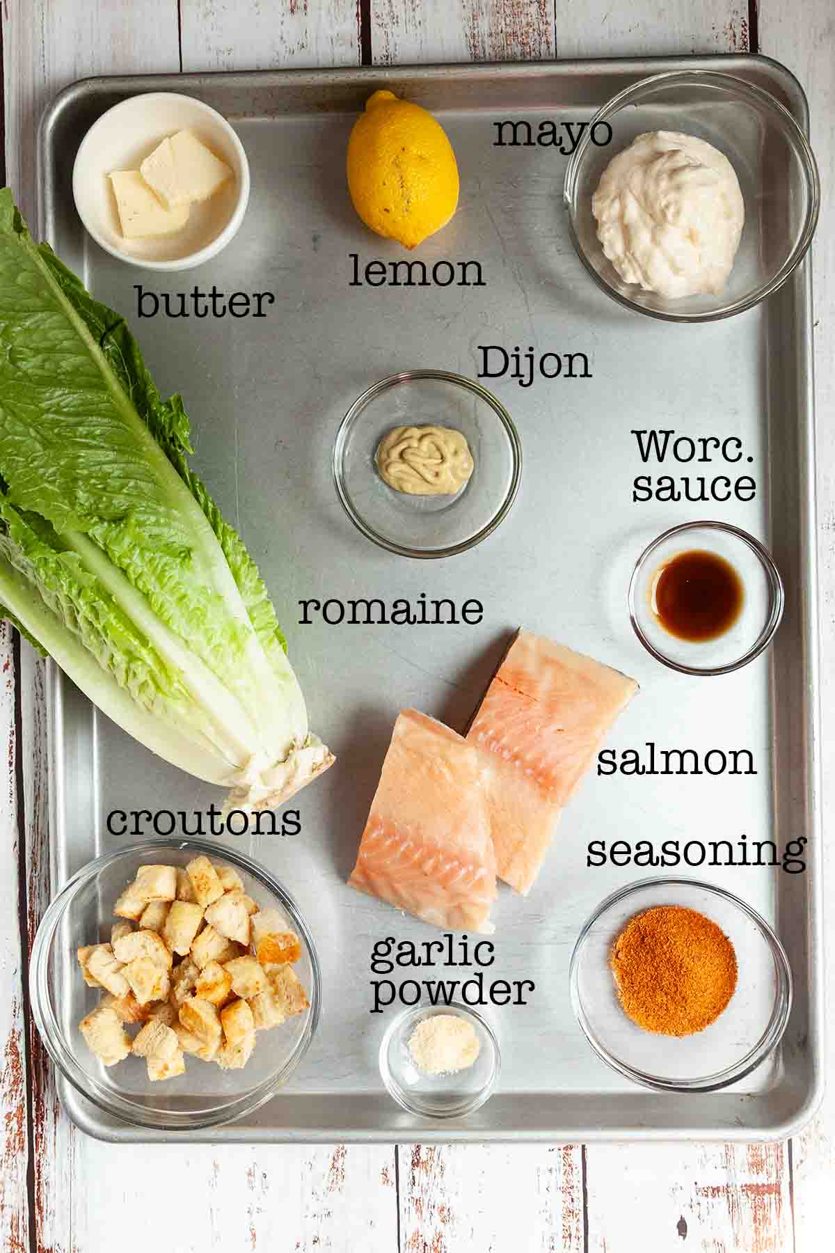 Ingredients for salmon Caesar salad--romaine, butter, lemon, mayo, Dijon, Worcestershire sauce, croutons, salmon, garlic powder, and seasoning.