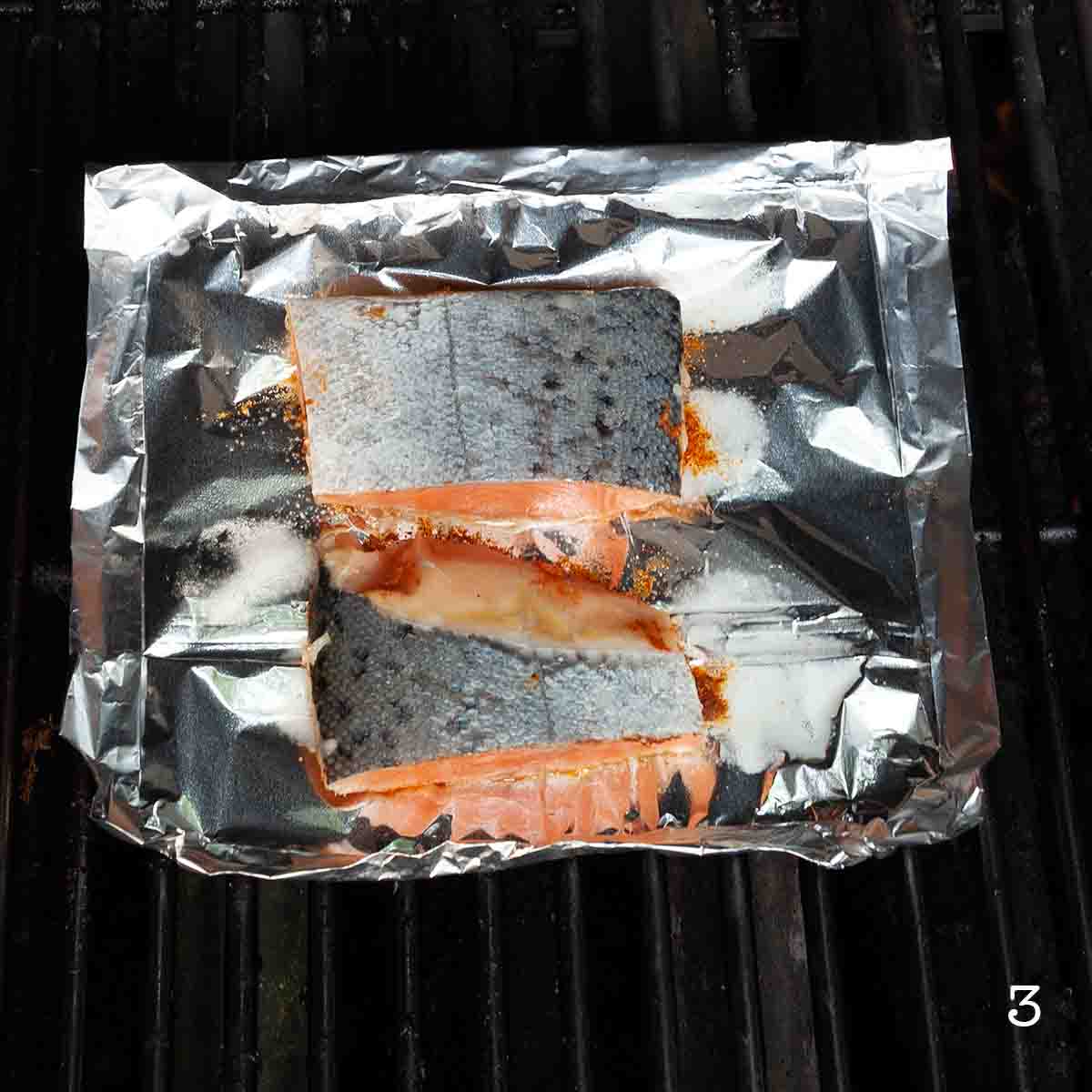 Two pieces of salmon cooking on the grill.