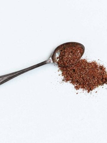 A spoonful of BBQ rub on a white surface.