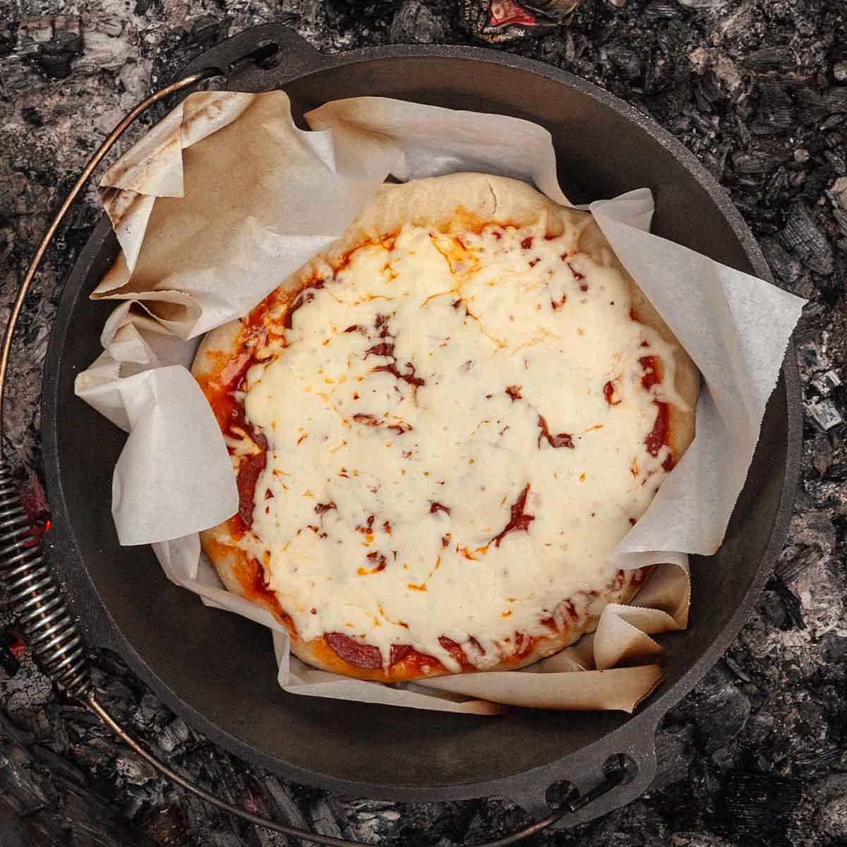 A cooked pizza in a Dutch oven.