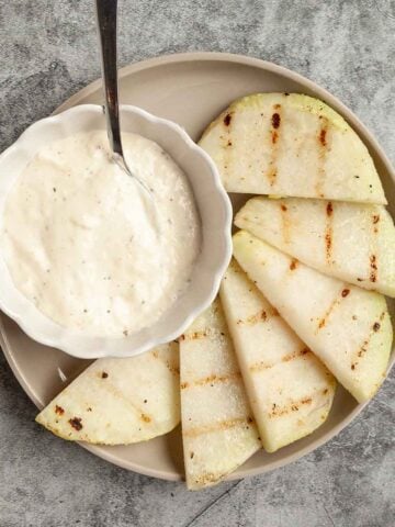 Half-moon slices of kohlrabi with a bowl of dip on the side.