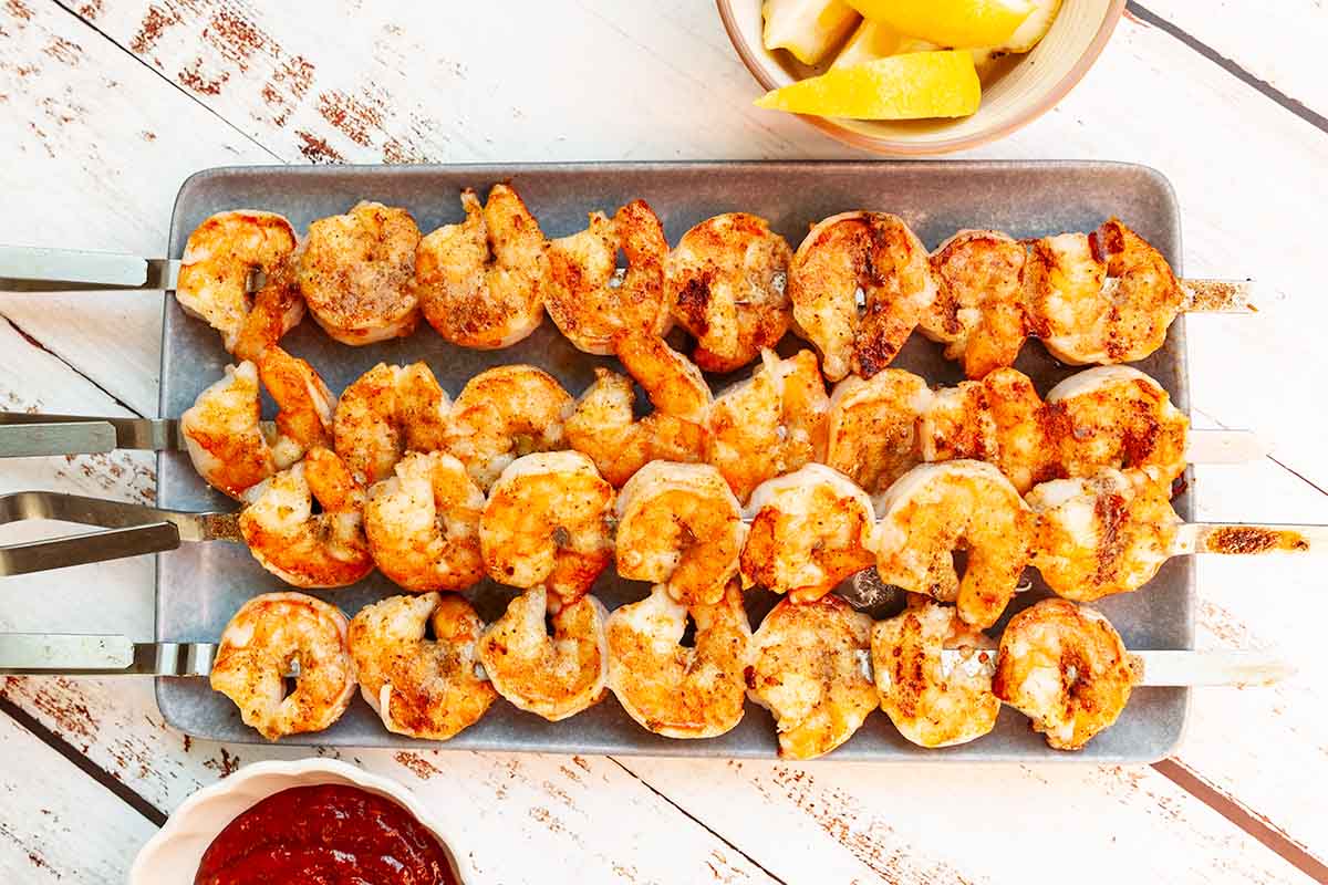 Four grilled shrimp skewers on a platter.