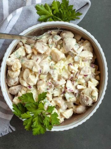 A bowl of potato salad with parsley on top.