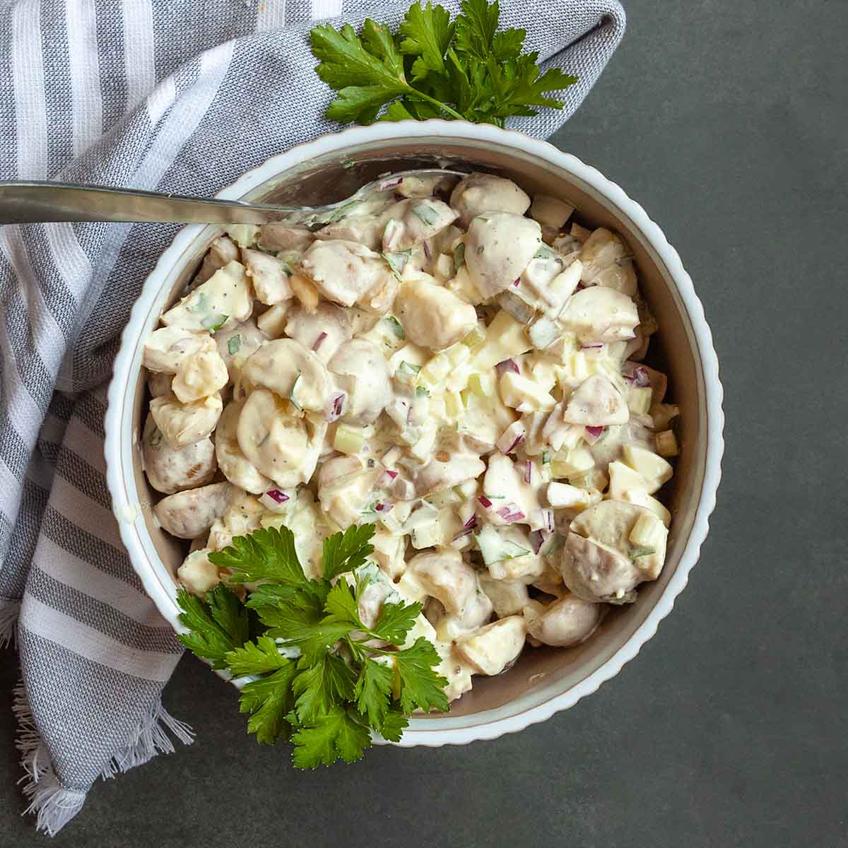 A bowl of potato salad with parsley on top.