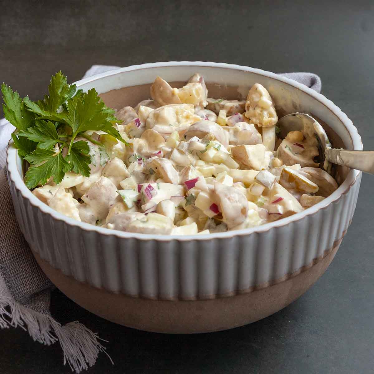 A bowl of potato salad with parsley on top.