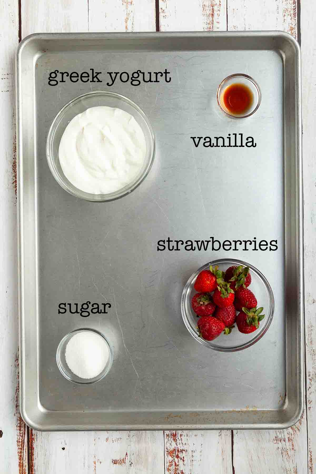 Ingredients for strawberry yogurt fruit dip--greek yogurt, vanilla, strawberries, and sugar.