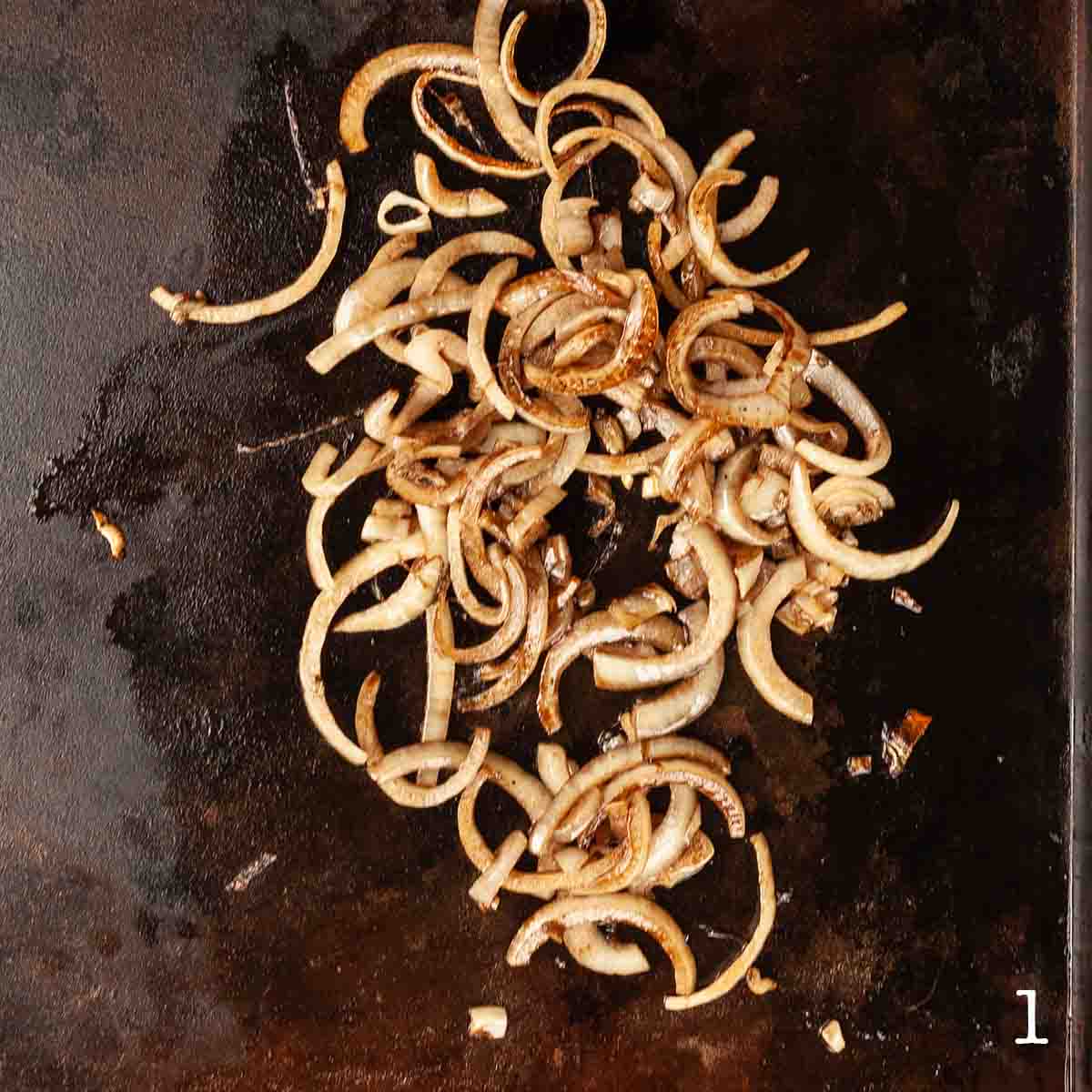 Sliced onions cooking on a Blackstone griddle.