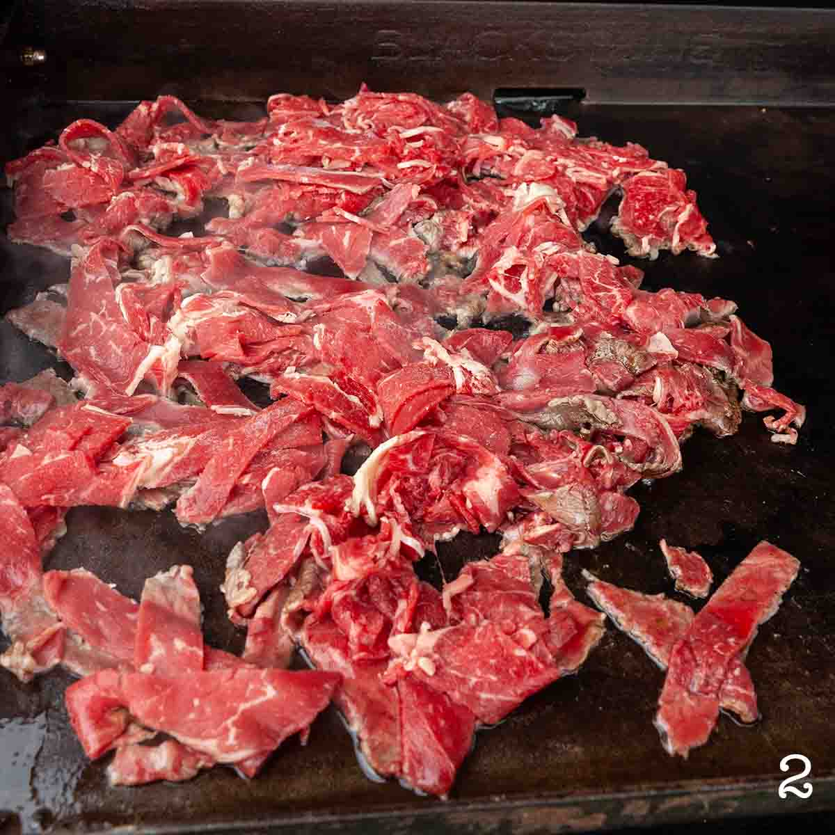 Rib eye cooking on a Blackstone griddle.