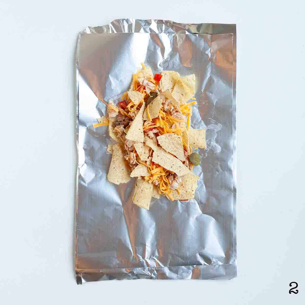 Chicken nachos assembled on a foil packet.