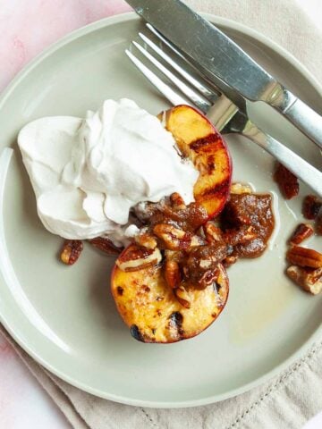 Two plates topped with grilled nectarines, candied pecans, and whipped cream.