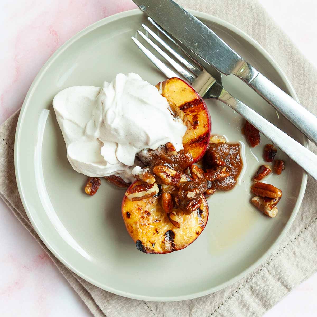 Two plates topped with grilled nectarines, candied pecans, and whipped cream.