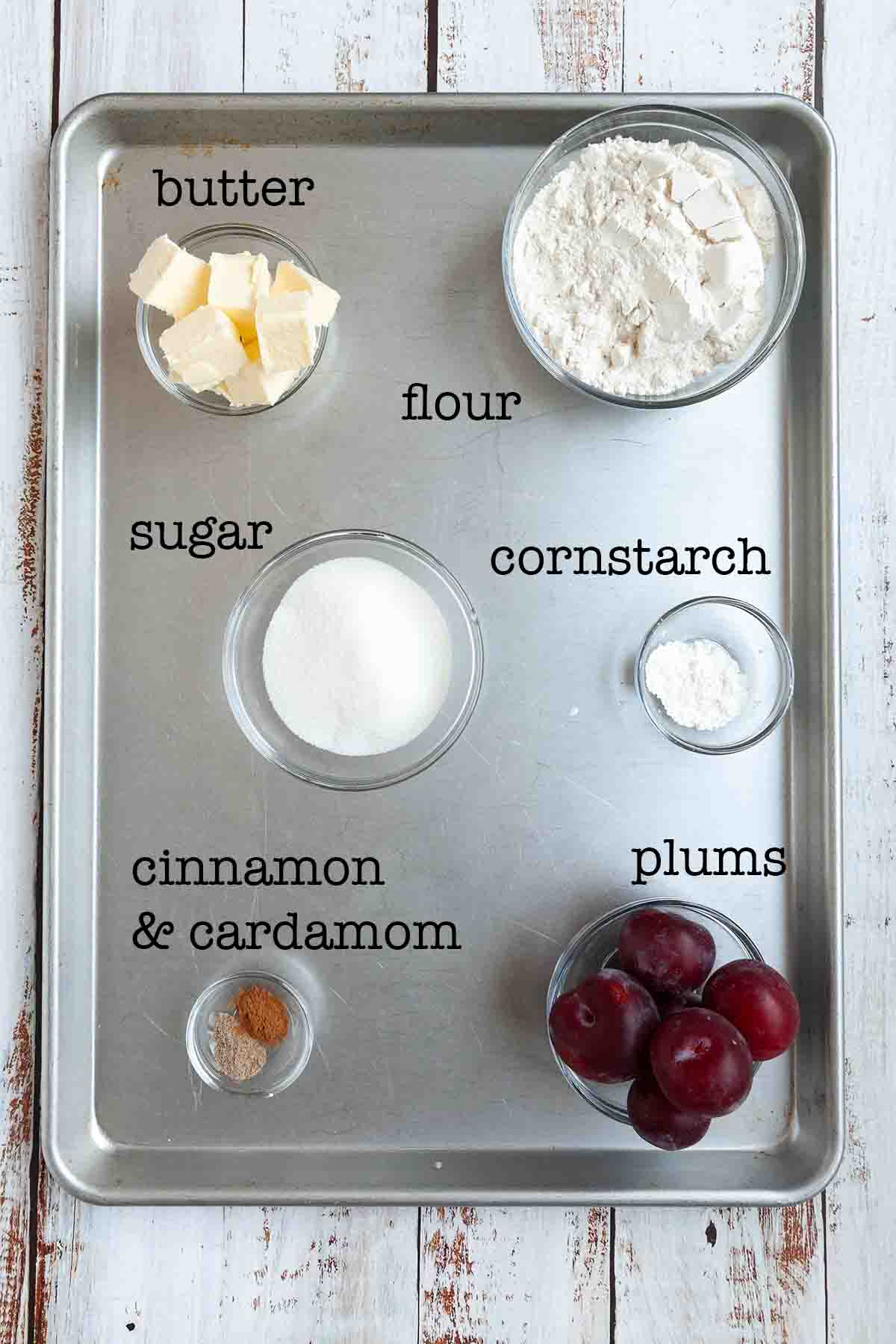 Ingredients for plum galette--butter, flour, sugar, cornstarch, cinnamon, cardamom, and plums.