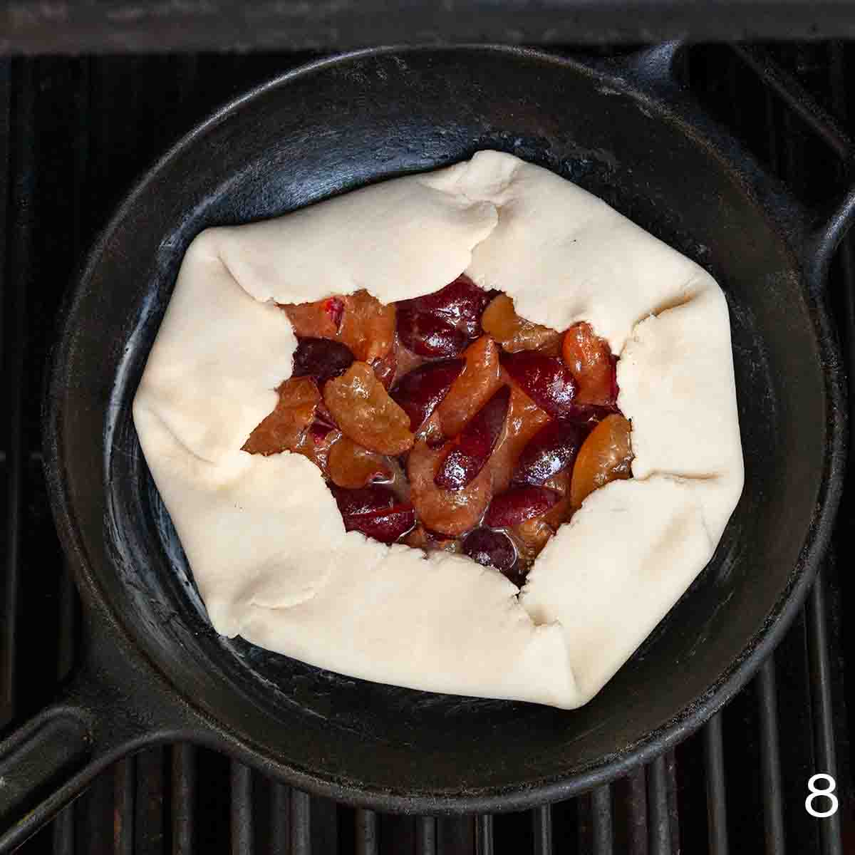 A plum galette in a cast iron skillet on the grill.