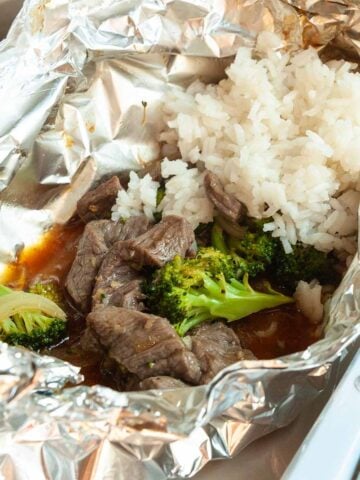 A foil packet with beef, broccoli, and rice.