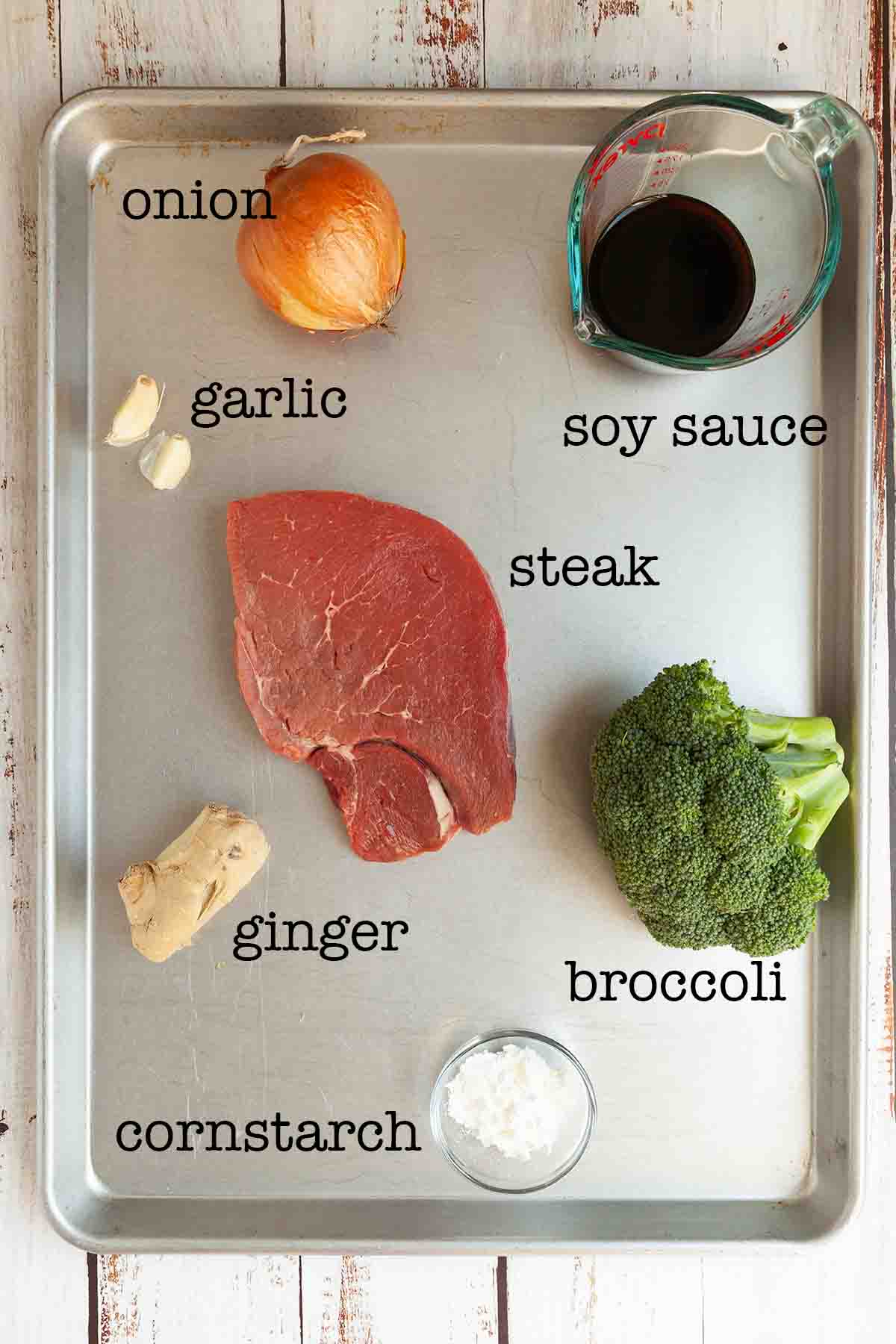 Ingredients for beef and broccoli foil packets--beef, garlic, onion, ginger, broccoli, soy sauce, and steak.