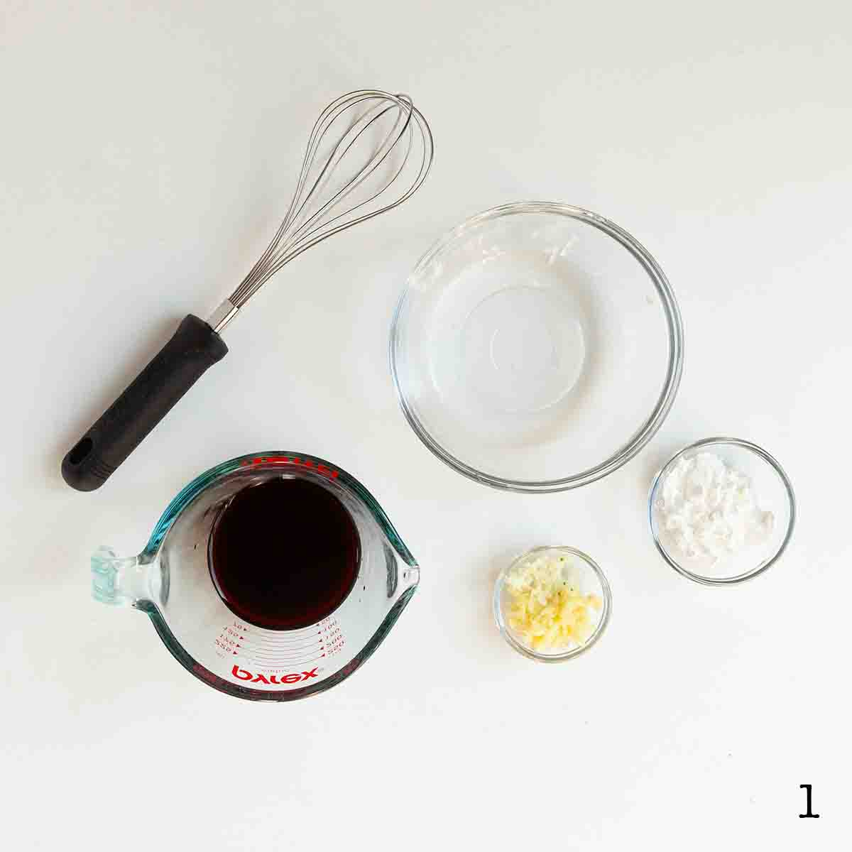 A bowl of ginger and garlic, cornstarch, and soy sauce with a whisk on the side.