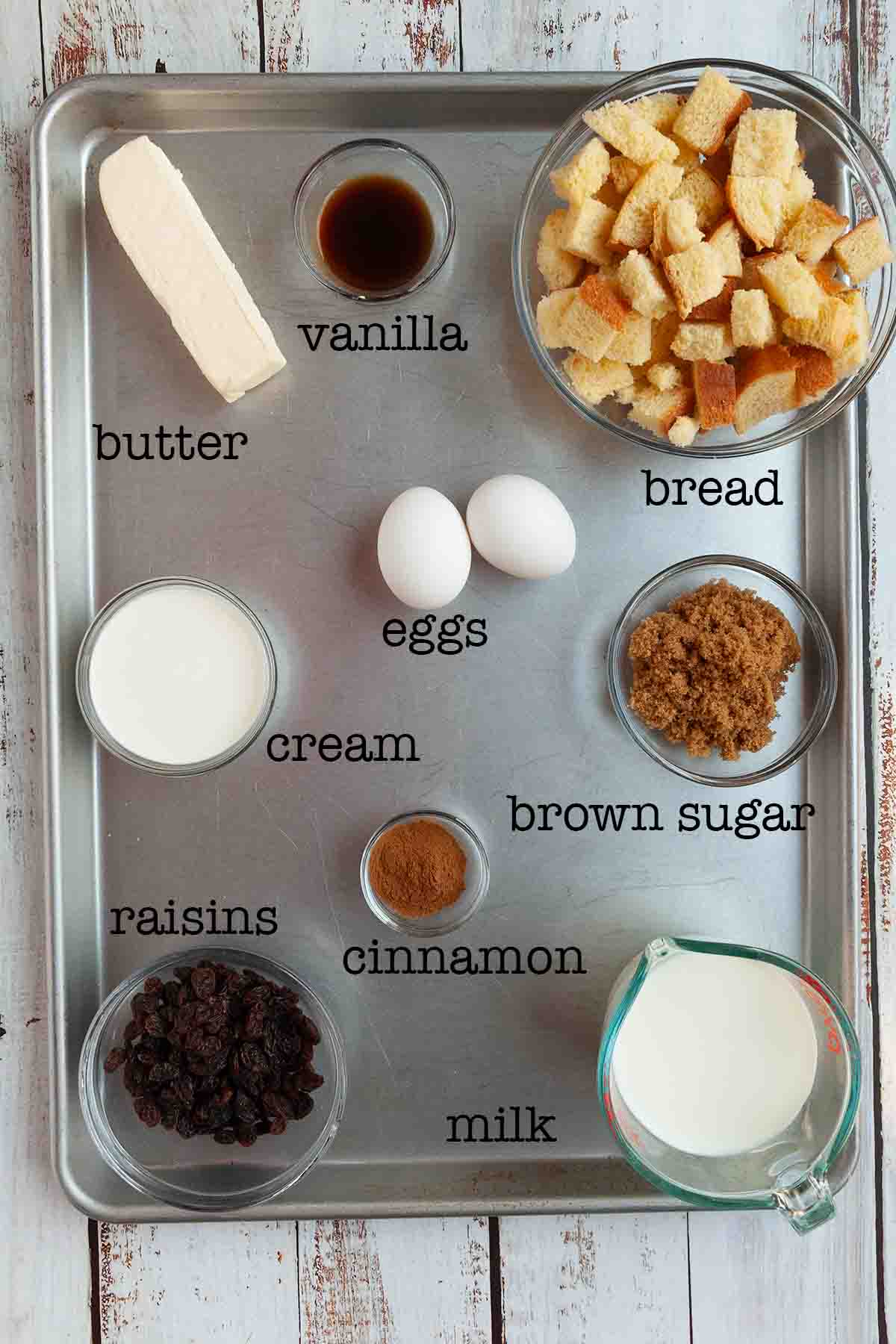 Ingredients for Dutch oven bread pudding--butter, vanilla, bread, eggs, cream, brown sugar, cinnamon, raisins, and milk.
