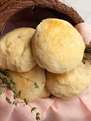 Dinner rolls with fresh thyme in a basket.