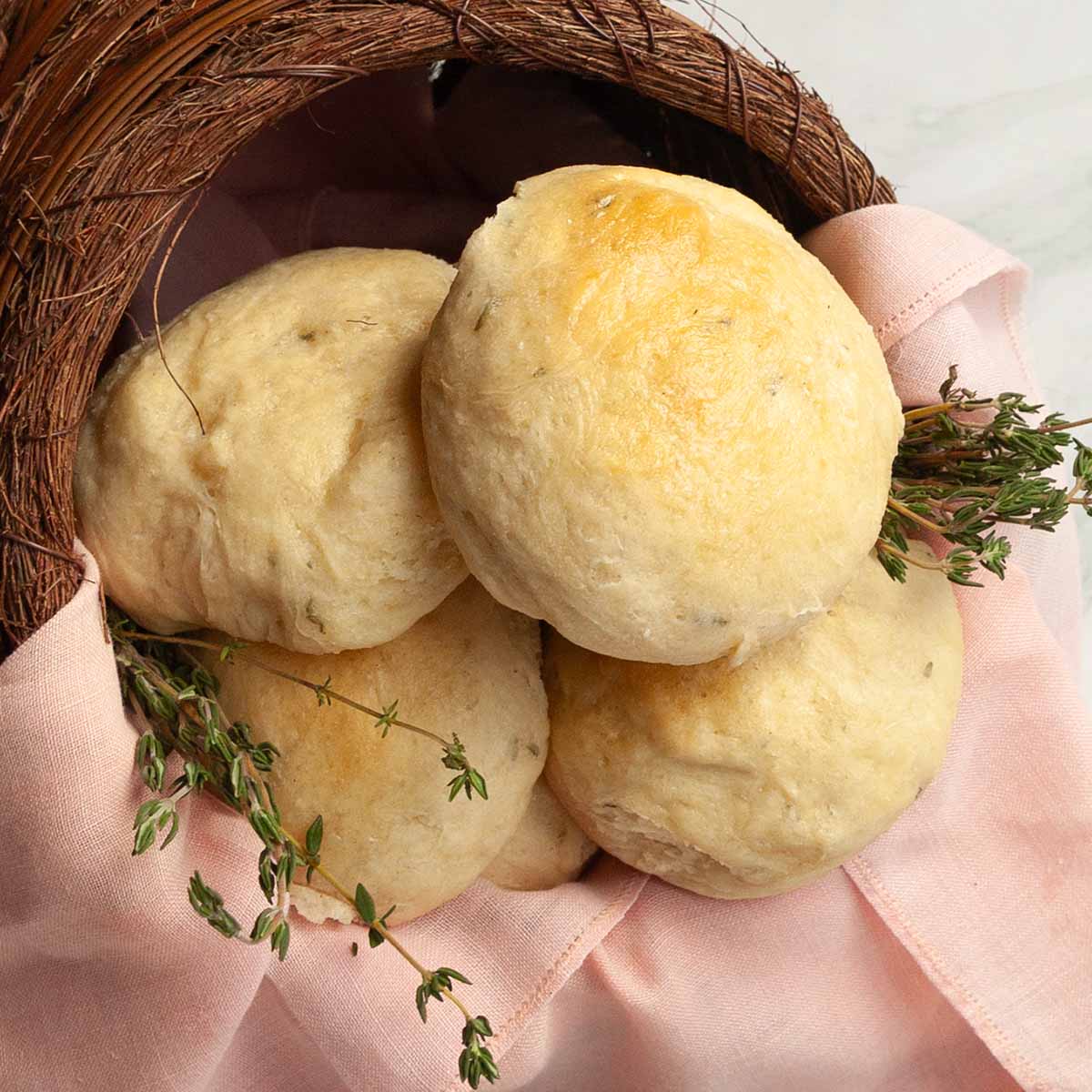 Dinner rolls with fresh thyme in a basket.