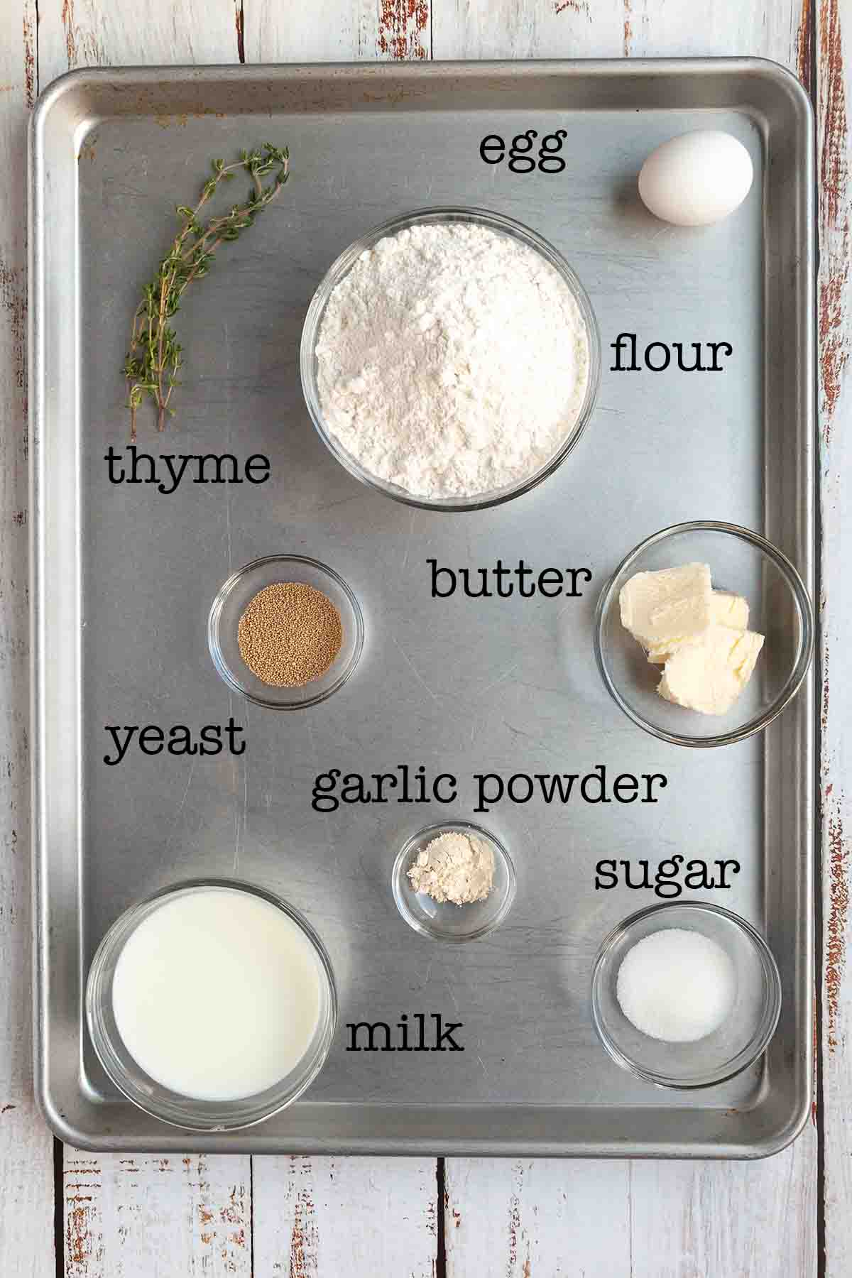 Ingredients for Dutch oven dinner rolls--thyme, flour, egg, yeast, butter, garlic powder, sugar, and milk.