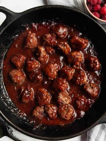 A skillet filled with meatballs in cranberry sauce.