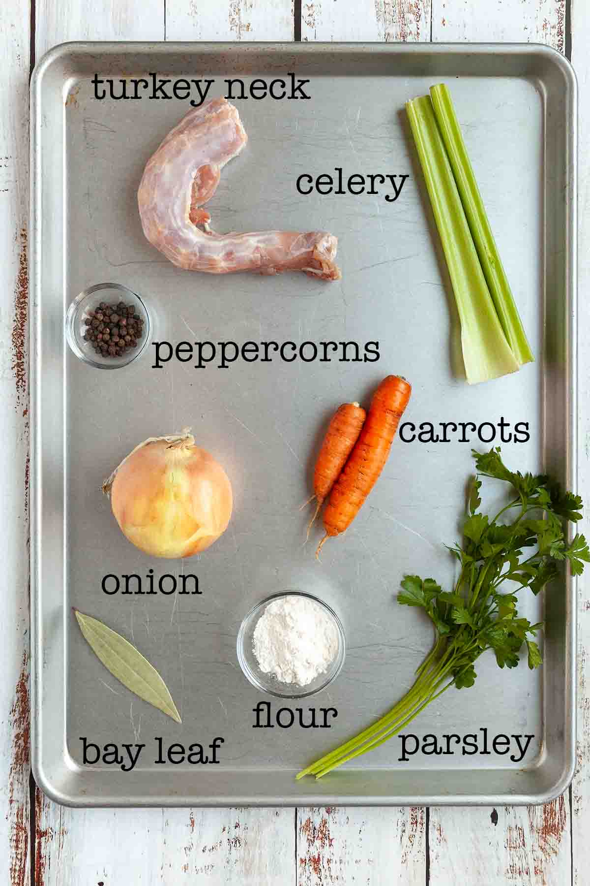 Ingredients for smoked turkey gravy--turkey neck, celery, peppercorns, carrots, parsley, flour, onion, and bay leaf.