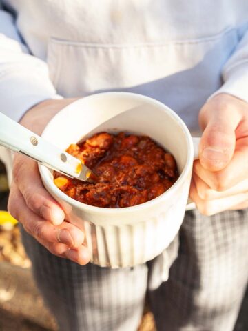 A person holding a mug of chili.