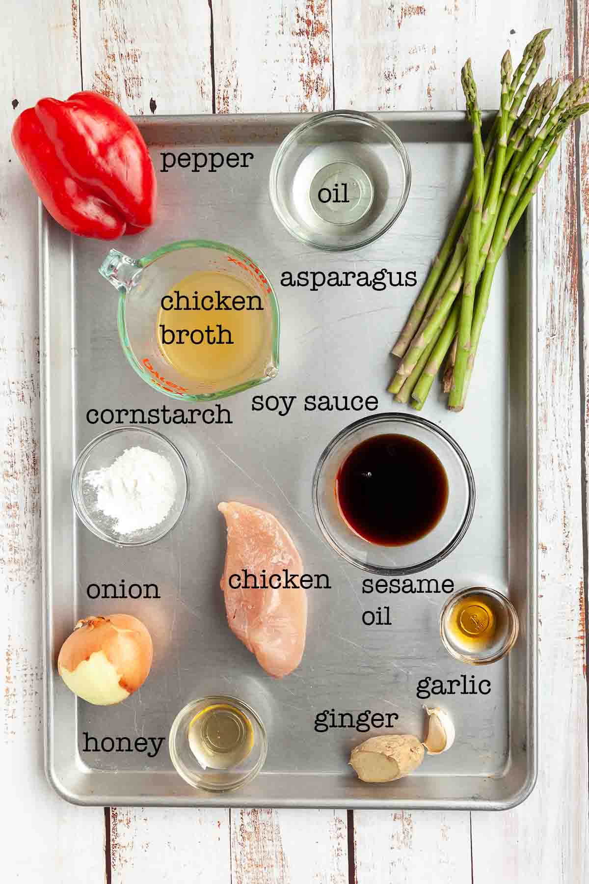 Ingredients for chicken stir fry--chicken, pepper, oil, broth, cornstarch, soy sauce, asparagus, onion, honey, ginger, and garlic.